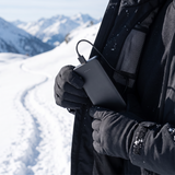 Hiker placing a slim black power bank into a heated jacket pocket