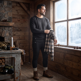 Man in a cabin wearing a black heated long johns base layer set