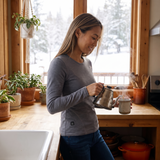 Woman in a winter kitchen wearing a gray heated thermal top