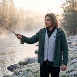 Man fly fishing at dawn with a gray quilted heated vest under his shell